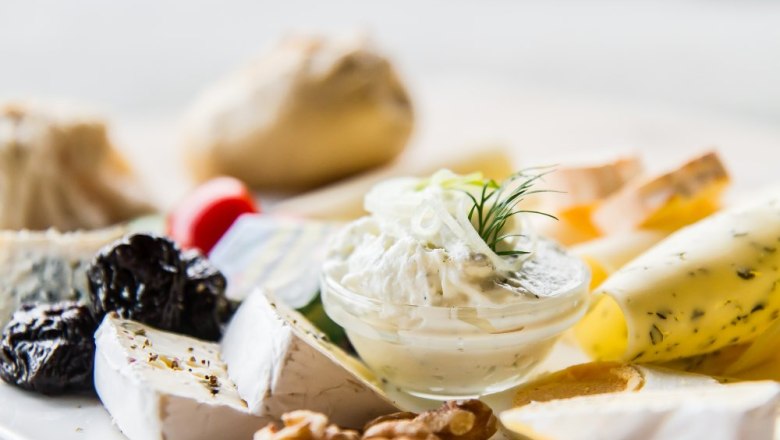 Käseplatte, © Weinberghof Ilkerl Nahaufnahme einer Käseplatte mit verschiedenen Käsesorten, Nüssen, Trockenfrüchten und einem Dip.