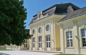 Conference Center Laxenburg, © Alois Dangl Historisches Gebäude mit gelber Fassade und großen Fenstern im Sonnenschein.
