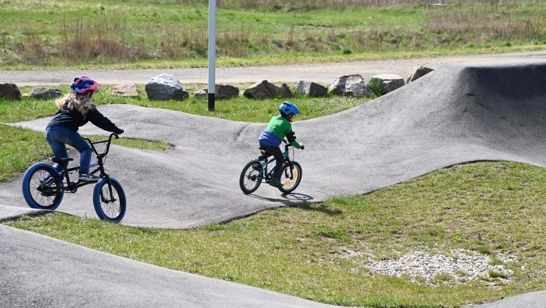 Pumptrack, © Markus Berger Zwei Kinder fahren mit Fahrrädern auf einem Pumptrack im Freien.