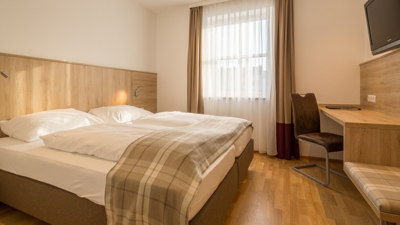 Hotel Unter den Linden Zimmer 215, © Hotel Unter den Linden Hotelzimmer mit Doppelbett, Schreibtisch und Fenster mit Vorhängen.