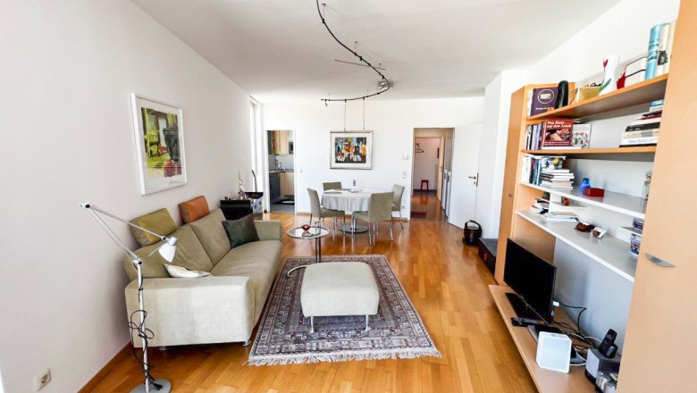 Apartment am Stadtpark, © Apartment am Stadtpark Modern eingerichtetes Wohnzimmer mit Sofa, Teppich, Esstisch und Bücherregal.