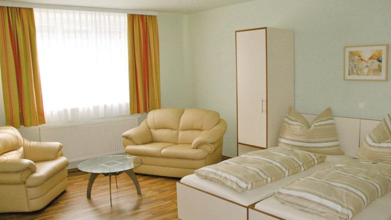 sonniges Doppelzimmer, © 2013. All Rights Reserved Helles Zimmer mit zwei Betten, Sofas, einem Tisch und einem Schrank.