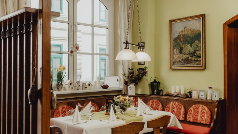 Urige Gaststube, © Niederösterreich Werbung/Sophie Menegaldo Gemütliche Gaststube mit gedecktem Tisch, Holzmöbeln und Dekorationen.