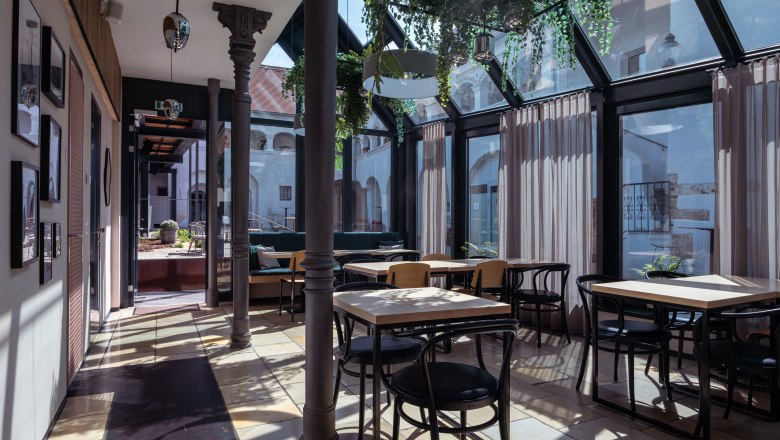 vierzigerhof, © Niederösterreich Werbung / Maximilian Pawlikowsky Innenansicht eines modernen Cafés mit Glasdach und Pflanzen.