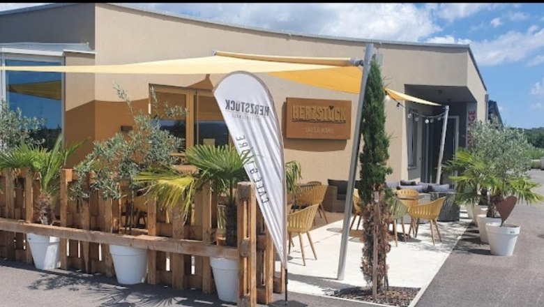 Aussenansicht Cafe Herzstück, © Cafe Herzstück_Stephanie Kirschner Außenansicht eines Cafés mit Terrasse, Sonnensegeln und Pflanzen.