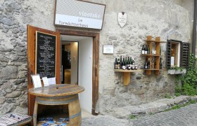 vinotake im Torwächterhaus, © Roman Zöchlinger Eingang zu einem Weinladen in einem alten Steingebäude mit Weinfässern und Weinflaschen an der Wand.