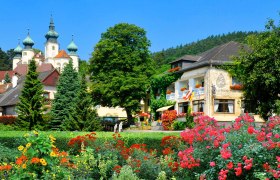 Hotel Restaurant Schlossgasthof Artstetten, © Schlossgasthof Artstetten Ein malerisches Hotel mit bunten Blumen im Vordergrund und einem Schloss im Hintergrund.