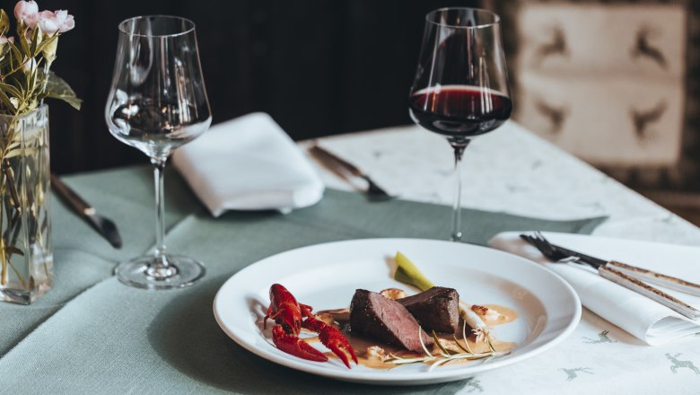 Erfrischend anders: Reh trifft Flusskrebs, © Niederösterreich Werbung/David Schreiber Elegantes Abendessen mit Fleisch, Flusskrebs und Rotwein auf gedecktem Tisch.