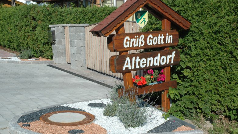 Altendorf, © Gemeinde Altendorf Willkommensschild mit der Aufschrift 'Grüß Gott in Altendorf' vor einer Hecke.