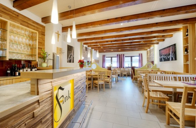 Heuriger Weinhof Fink, © Philipp Monihart Innenansicht eines gemütlichen Gastraums mit Holzmöbeln und Theke im Heurigenstil.