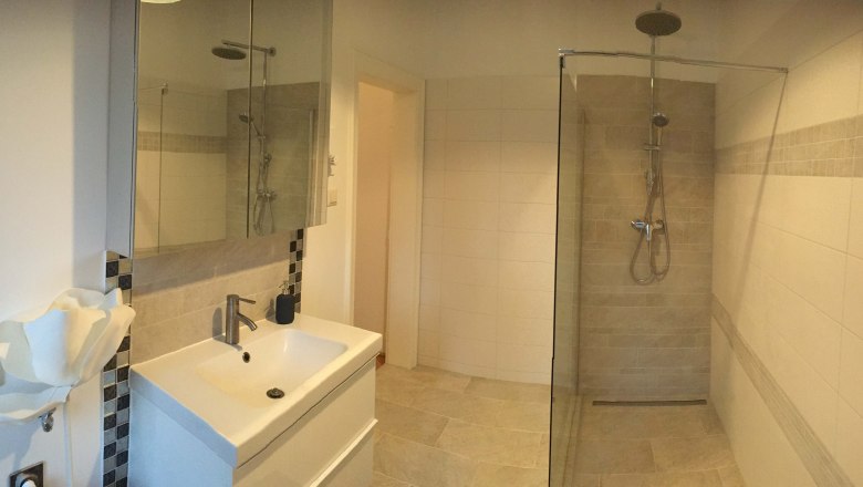 Bad, Apartment Sacher, © Petra Sacher Modernes Badezimmer mit Dusche, Waschbecken und Spiegel.