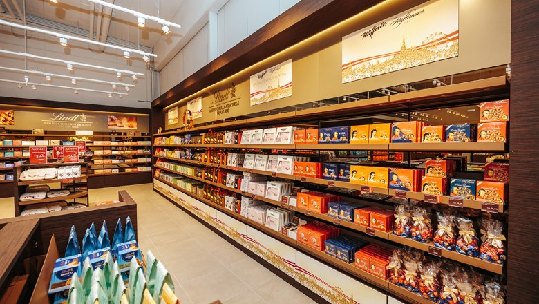 Lindt & Sprüngli Shop, © Philipp Lipiarski Innenansicht eines Lindt & Sprüngli Shops mit Regalen voller Schokolade und Süßigkeiten.