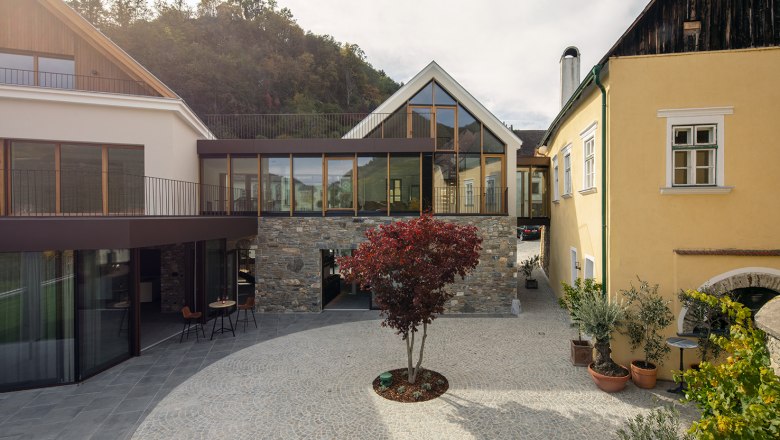 Mauritiushof Weinerlebniswelt Gartenansicht, © Weingut FJ Gritsch Gartenansicht des Mauritiushofs mit modernem Gebäude und gepflastertem Hof.