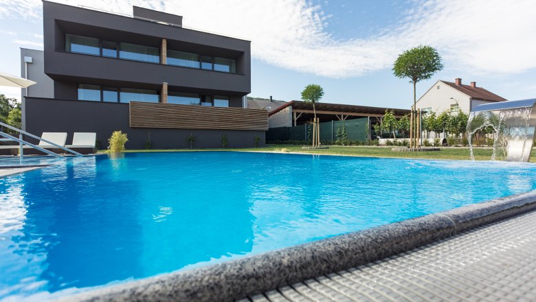 Weinlodge mit Pool im Vordergrund, © KASTNER NEW MEDIA - kastner.tv Modernes Gebäude mit Pool im Vordergrund und blauem Himmel im Hintergrund.