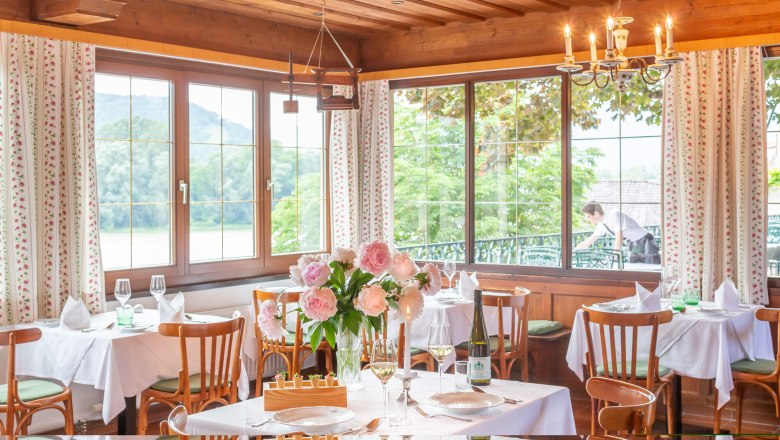 Restaurant Hotel Richard Löwenherz, © Chris Saupper Elegantes Restaurant mit gedeckten Tischen, Blumen und Blick auf die Natur durch große Fenster.
