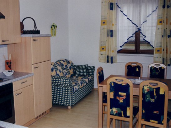 FW Weinstock, © Familie Mörtinger Wohnzimmer mit Küchenzeile, Sofa und Esstisch.