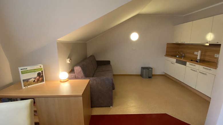 Ferienwohnung Herbst, © Privatzimmer Leeb Innenansicht einer Ferienwohnung mit Sofa, Tischlampe und Küchenzeile.