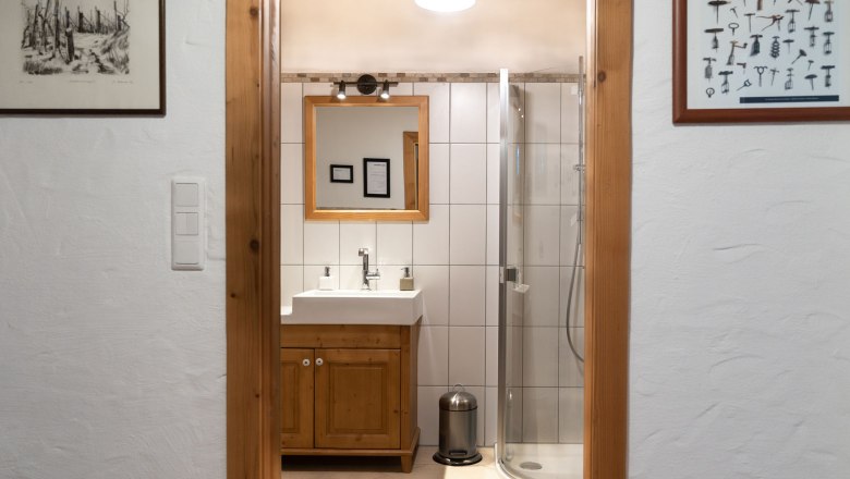 Badezimmer mit Dusche, © Weinakademie Retz Blick durch eine Tür auf ein Badezimmer mit Dusche, Waschbecken und Spiegel.