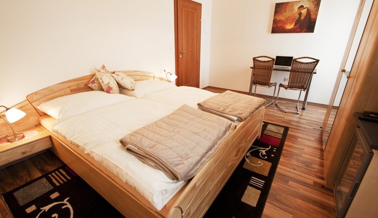 Doppelzimmer, © Pension Theresa Ein gemütliches Doppelzimmer mit Holzboden, Doppelbett, Schreibtisch und Stühlen.