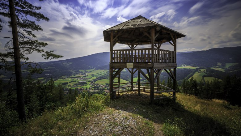 Kernstockwarte Kirchberg am Wechsel, © Wiener Alpen, Foto: Christian Kremsl Holzaussichtsturm mit Blick auf grüne Täler und Berge unter blauem Himmel.