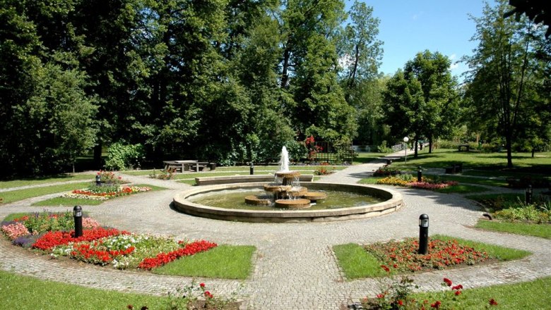 Stadtgemeinde Groß-Siegharts, © Stadtgemeinde Groß-Siegharts Ein gepflegter Park mit einem zentralen Brunnen, umgeben von Blumenbeeten und Bäumen.
