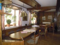 Privatzimmer Karl Mandl, © Familie Mandl Ein traditionell eingerichtetes Zimmer mit Holzmöbeln, Pflanzen auf der Fensterbank und hängenden Lampen.