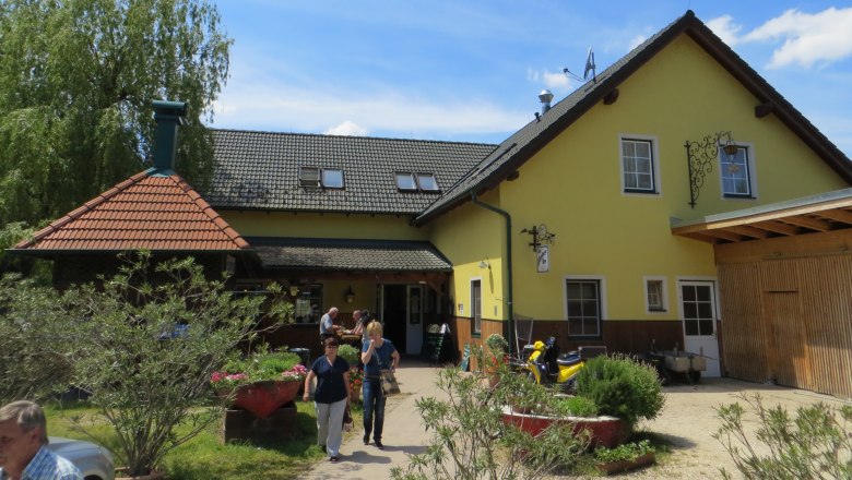 Gasthof Oase am Teich, © Urani Ein gelbes Gasthaus mit grauem Dach und Garten im Vordergrund.