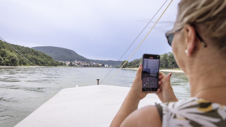 Event Schifffahrt Haider, © Donau Niederösterreich, Barbara Elser Frau auf einem Boot fotografiert die Donau mit ihrem Handy.