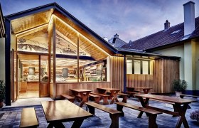 Weingut Ott, © www.spitzbart.at Modernes Weingut mit Holzelementen und Außenbereich bei Dämmerung.