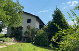 Privatzimmer Haus Köhler, © Wiener Alpen Ein zweistöckiges Haus mit Garten und Bäumen, bei sonnigem Wetter.