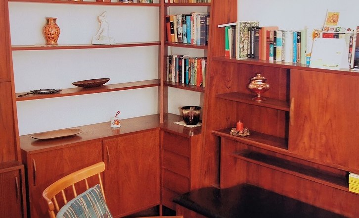 Bibliothek, © Wiener Alpen Gemütliche Leseecke mit Holzregalen, Büchern und einem Sessel.