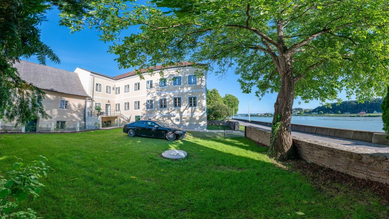 Altes Postamt Aussenansicht mit Donau, © Aumüller Caroline Außenansicht eines alten Postamts mit Baum und Auto im Vordergrund, Donau im Hintergrund.