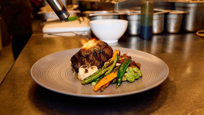 Wolfgang Puck Kitchen + Bar, © Flughafen Wien Wolfgang Puck Kitchen + Bar, Fleisch wird am Teller flambiert