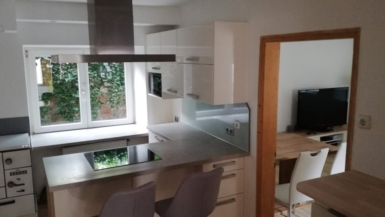 Küche, © Günter Lammer Moderne Küche mit Kochinsel, weißen Schränken und Fenster mit Blick ins Grüne.