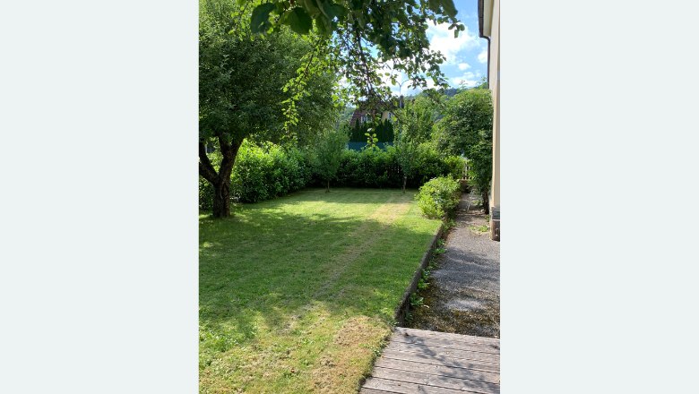 Garten Haus Zwei, © Familie Wochesländer Ein gepflegter Garten mit Rasen, Bäumen und Sträuchern neben einem Haus.