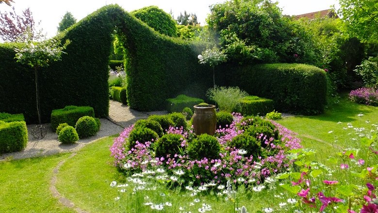 dscf3768_sl_c_natur-im-garten-schaugaerten, © "Natur im Garten" Schaugärten Ein gepflegter Garten mit Hecken, Blumenbeeten und einem großen Keramiktopf in der Mitte.