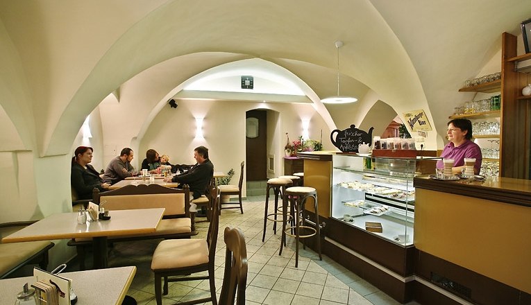 Café Colibri, © Susanne Karas Innenansicht eines gemütlichen Cafés mit gewölbter Decke, Tischen und einer Theke.