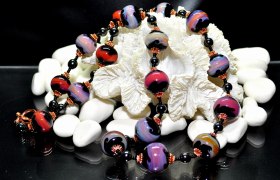 kunst-trifft-handwerk_01, © Monika Hartl Bunte Perlenkette auf weißen Steinen und Muschel.