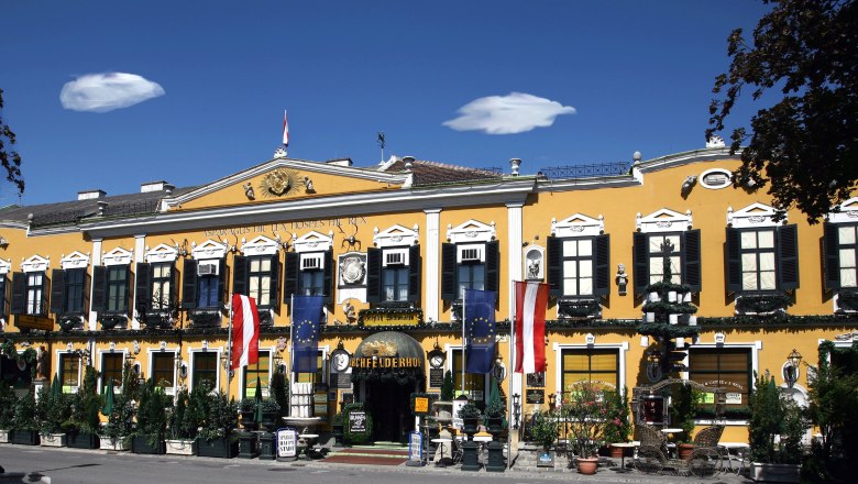 Marchfelderhof, © Gault Millau Gelbes Gebäude mit schwarzen Fensterläden und österreichischer Flagge.