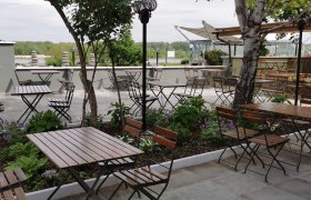 Gastgarten Taverna, © Taverna Gastgarten mit Sitzmöbeln im Hintergrund die Donau