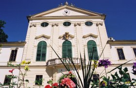 Schloss Kirchstetten, © Marktgemeinde Neudorf bei Staatz Fassade von Schloss Kirchstetten mit grünen Fensterläden und Blumen im Vordergrund.