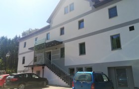 Gasthaus Grandits, © Wiener Alpen Außenansicht eines modernen Gasthauses mit mehreren Fenstern und parkenden Autos davor.