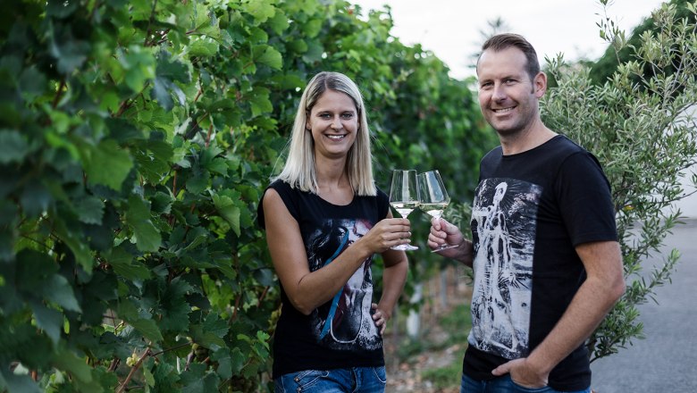 Weingut Leopold Figl, © David Schreiber Zwei Personen stoßen mit Weingläsern in einem Weinberg an.