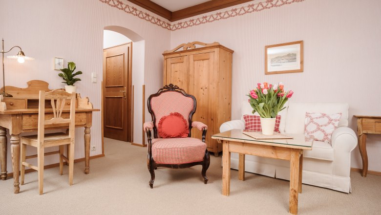 Landhaus Bacher, © Best of Wachau_Rita Newman Gemütliches Wohnzimmer mit Holzmöbeln, einem Sessel, Sofa und Tisch mit Tulpen.