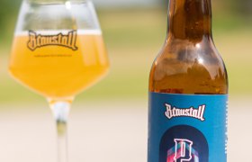 braustall_brewday, © Hofbrauerei Braustall_Georg Schwameis Eine Flasche Braustall Pale Ale und ein Glas mit Bier auf einem Tisch im Freien.