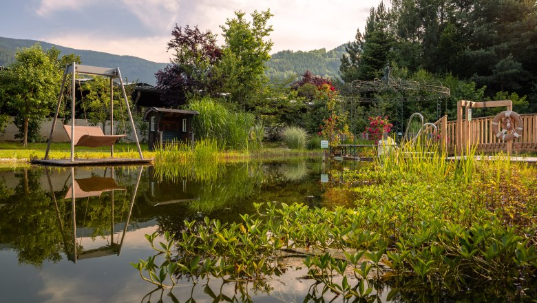 Naturhotel Molzbachhof, © Niederösterreich Werbung / Maximilian Pawlikowsky Ein idyllischer Garten mit Teich, Schaukel und üppiger Vegetation im Naturhotel Molzbachhof.