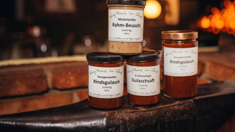 Wirtshaus für Zuhause, © Niederösterreich Werbung/Daniela Führer Drei Gläser mit Fertiggerichten auf einem Amboss, beschriftet mit 'Wirtshaus im Glas'.