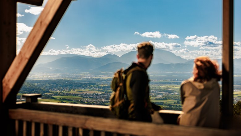 Am Aussichtsturm in Lanzenkirchen/Wiesen, © Wiener Alpen/Fülöp, Kremsl Zwei Personen stehen auf der Plattform des hölzernen Aussichtsturmes Lanzenkirchen/Wiesen, im Hintergrund ist eine weite Ebene und am Horizont der Schneeberg gut erkennbar.