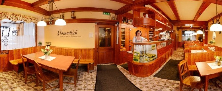 Gaststube, © Gasthof Schmirl Panorama einer gemütlichen Gaststube mit Holzmöbeln und dekorativen Lampen.