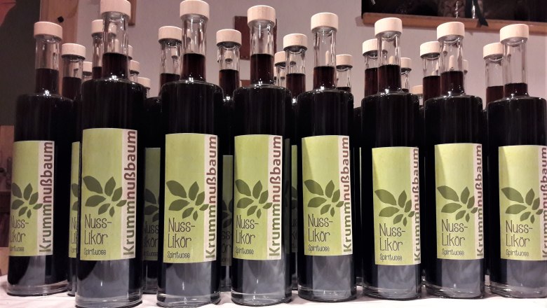 Nusslikoer classic, © Johann Peham Reihe von Flaschen mit Nusslikör und grünen Etiketten.